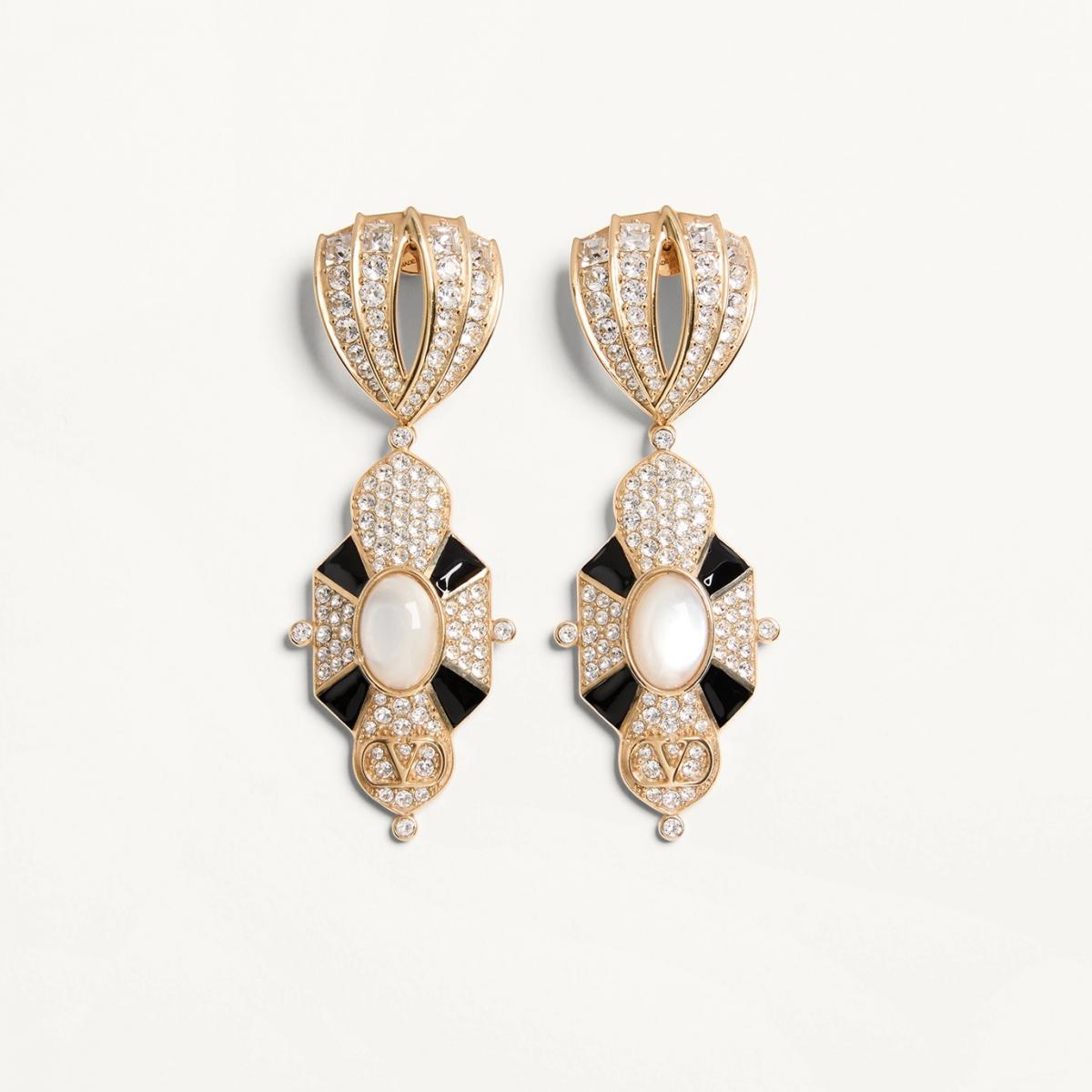 Valentino 的 Pas Plus 系列將復古與未來融合成一場光的盛宴。黑色的琺瑯與奶油色的樹脂珍珠，襯托出中世紀般的華麗，密鑲人造水晶在金色輪廓間閃爍，像一場歌劇的開場。它適合那種懂得駕馭繁複細節的女人，就像謝盈萱的氣質，能在安靜中綻放強烈存在感。