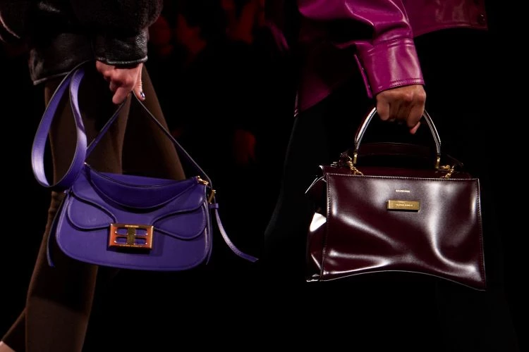 配件向來是每場大秀最受矚目的焦點之一。這一季，影像敘事也從服裝一路延伸至包款設計。例如品牌經典機車包 City Bag 在本季加入亮面皮革，並結合 Sam Levinson 的影像圖像，包身在燈光下呈現出流動般的光影效果，在整排深色造型之間多了一抹帶著叛逆氣息的浪漫。