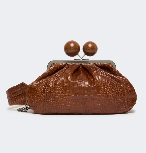 這款手提包採用棕色鱷魚紋皮革製成，並搭配了兩個木質球形扣環和一條金屬鍊條，完美演繹了「剛柔並濟」的時尚美學。不論是精緻的手提或率性的肩背，都能瞬間提升穿搭層次，營造出優雅且充滿個性的迷人丰采。（商品價格約：NTD 22,200）