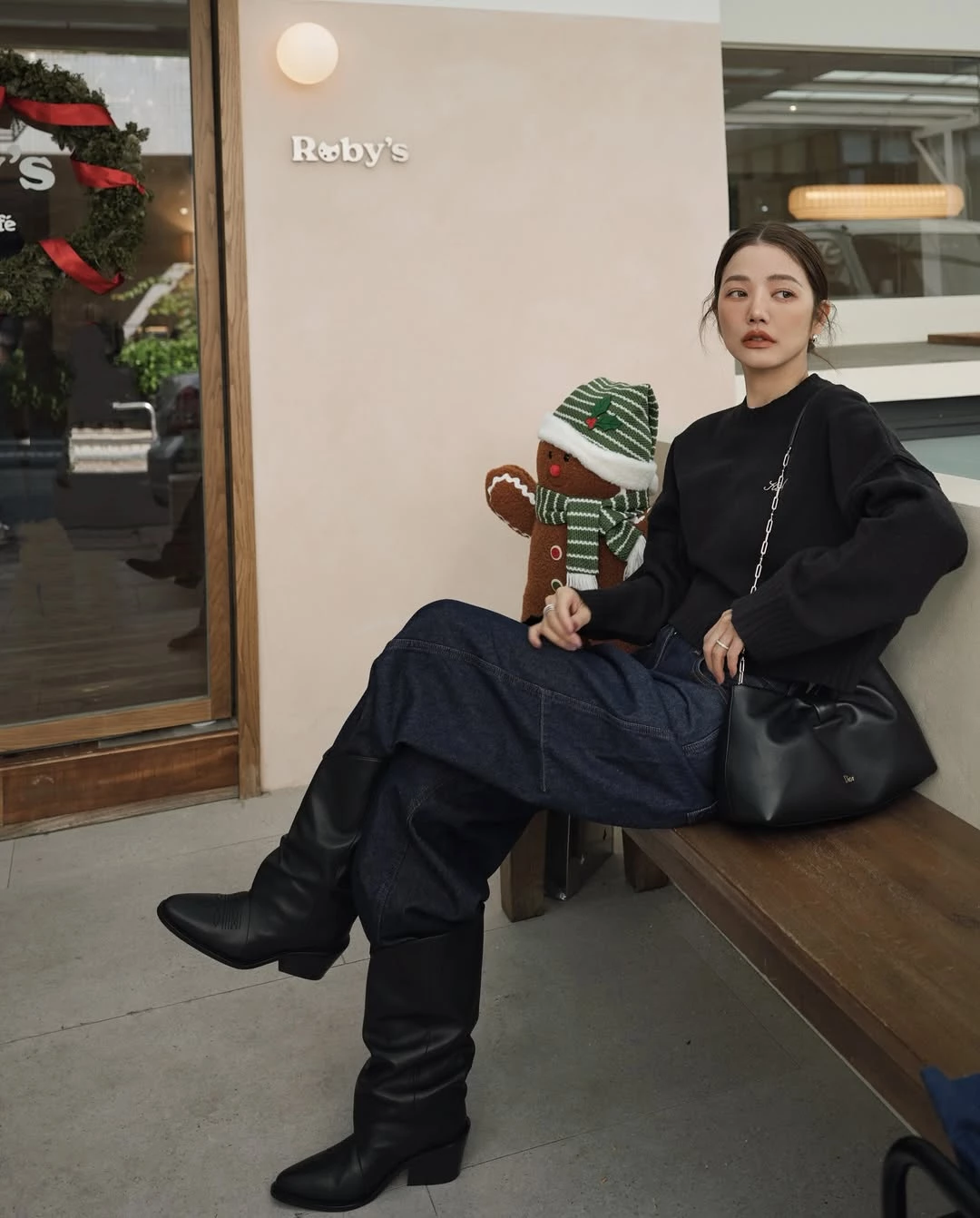 黑色穿搭若搭配得當，其實反而更能凸顯俐落與年輕。許路兒以寬鬆黑色針織上衣搭配深色丹寧褲，整體線條偏向休閒風格，透過寬鬆輪廓營造自然的隨性氛圍。這類造型的關鍵在於「不過度修飾」，反而讓整體看起來更自在，也更符合日常生活的節奏。腳下搭配黑色長靴，使整體線條更顯俐落，也為造型增加一點率性氣質。包款則是 Dior Bow Bag，這款在2026春夏系列登場的新包，以立體蝴蝶結作為視覺焦點，柔軟包身結合細膩皮革工藝，既保留法式優雅，也帶有現代感。黑色款搭配低調金色 Dior 標誌與金屬鏈帶肩背設計，使整體造型在簡約之中多了一點精緻度。當服裝保持低調時，一只設計鮮明的包款往往就能成為整體亮點，也讓日常休閒造型看起來更有層次。