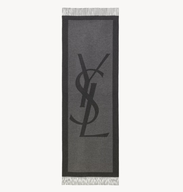 這條由石墨色與深灰色組成的長方形圍巾，在布料中間飾有超大的YSL Cassandre字母緹花設計，讓人一眼就能看出是來自哪個精品，低調又帶有強烈辨識度。