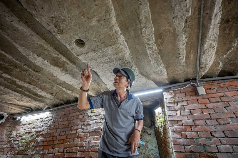 導覽人員指著甬道內的波浪狀設計解釋其消音作用。（圖／焦正德攝）