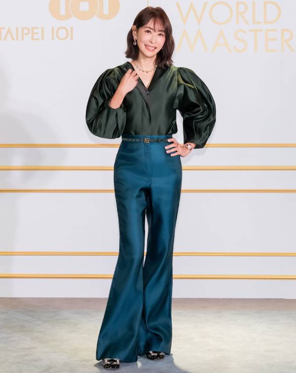 光是賈永婕這套造型，便是精彩演繹了她對於高階撞色的運用所帶來的減齡效果。她大膽選擇沉穩卻自帶光澤感的森林綠澎袖上衣，搭配亮眼的孔雀藍高腰喇叭褲，冷色調之間的撞色組合不僅襯托出白皙膚色，也在視覺上堆疊出細緻的層次美感。