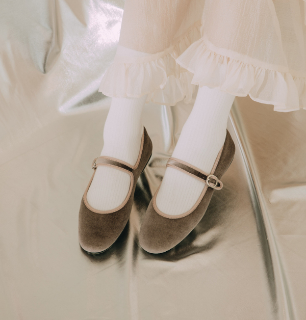 散發淡雅浪漫氣息的Grace Gift粉藕色瑪莉珍平底鞋，以細緻絨布質地詮釋柔和氛圍，低調中透出迷人質感。圓潤優雅的鞋楦線條自然修飾腳型，悄悄拉提整體比例，讓步伐間多了幾分輕盈與秀氣。