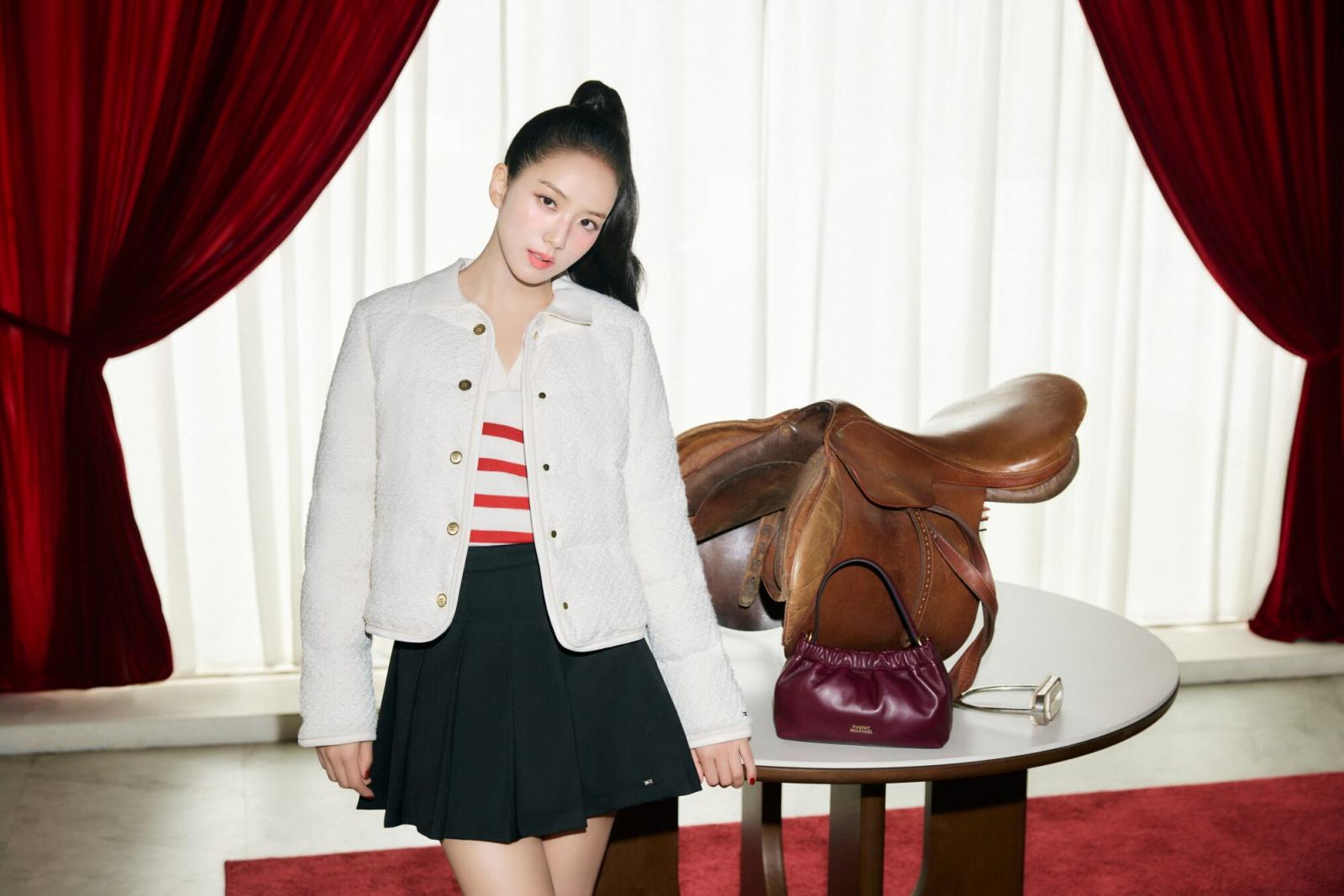 在多數人的印象裡，新年紅總是越多越好，但 Jisoo 這次示範的，反而是「紅色退一步」的穿法。她選擇以紅白條紋針織 Polo 作為內搭，讓紅色只存在於上半身的視覺焦點，既保留節慶象徵，也不會過度張揚。外層搭配象牙白絎縫外套，成功中和紅色熱度，也讓整體氛圍顯得清爽、乾淨。白色在這裡不只是陪襯，而是負責「降溫」與「定調」，讓紅色顯得更加細膩。下身搭配黑色百褶迷你裙與樂福鞋，則穩住整體比例，避免造型過度甜膩。這種配色邏輯特別適合過年走親訪友、需要長時間穿著的場合，不會因為顏色過重而產生視覺疲勞。對平常不習慣穿大紅的人來說，這是一個非常友善、也最不容易出錯的入門方式。