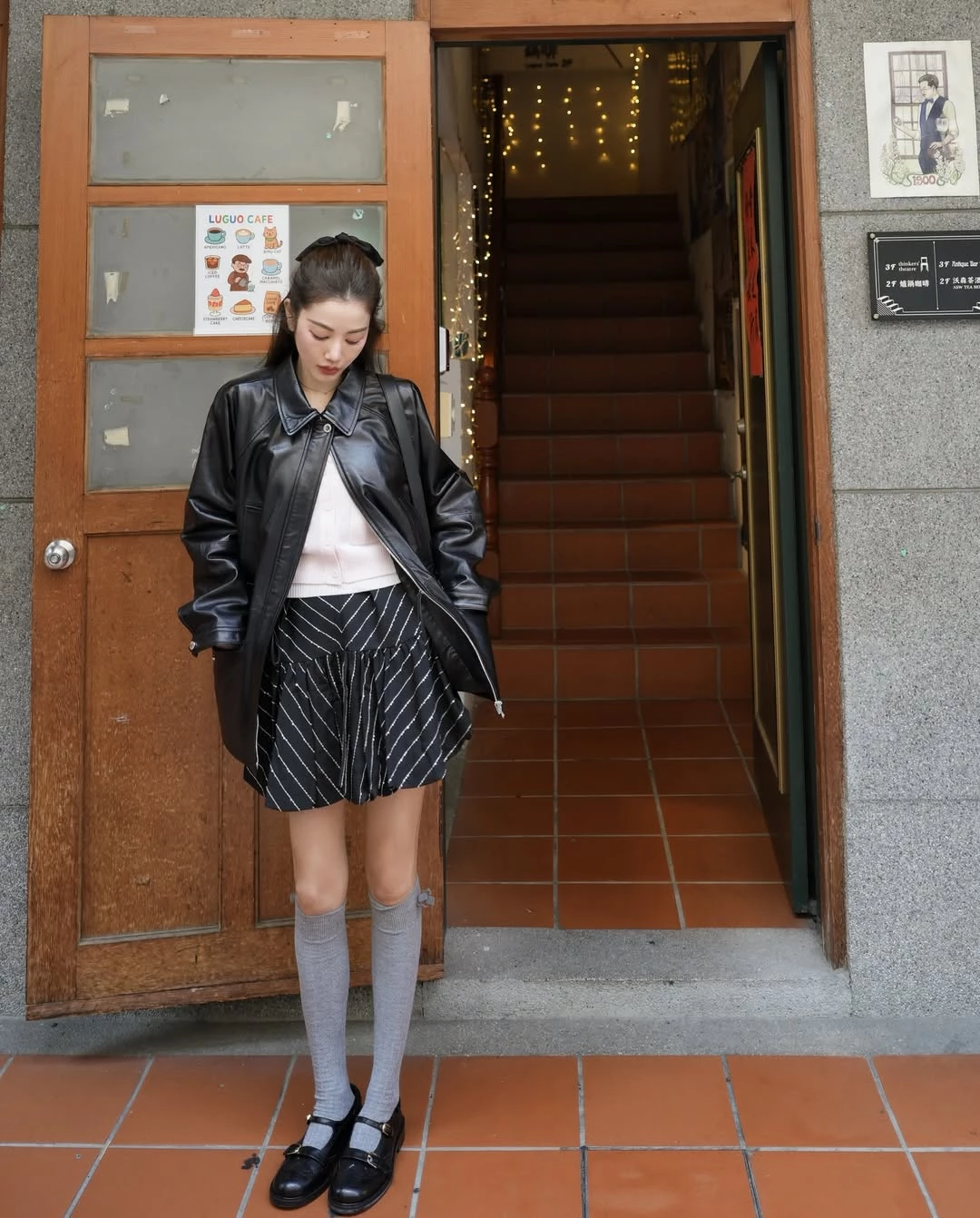 想把少女感單品穿得時髦而不顯幼稚，關鍵在於單品之間的風格平衡。許路兒以 Sandro 的黑色皮革外套搭配條紋澎裙，利用皮革的俐落與硬挺質感，為裙裝的輕盈輪廓增添一點率性。內搭簡潔粉色針織上衣讓整體線條保持乾淨，而灰色長襪與瑪莉珍鞋則帶出淡淡的學院氣息，也讓腿部比例看起來更加修長。這種帥氣單品與少女元素的混搭方式，能讓造型既有層次，又保留輕盈感。包款部份，她選擇的是同樣來自 Sandro 的 Le Mambo Shoulder Bag，這款肩背包以平滑皮革打造，搭配簡約弧形翻蓋與金屬旋轉扣設計，線條俐落又帶點復古氣息。包身比例修長，容量實用，既能肩背也能斜背，十分符合日常穿搭需求。當整體造型已經有澎裙與長襪等細節時，這種設計簡潔的包款反而更能穩住視覺焦點，也讓整體風格看起來更加耐看。