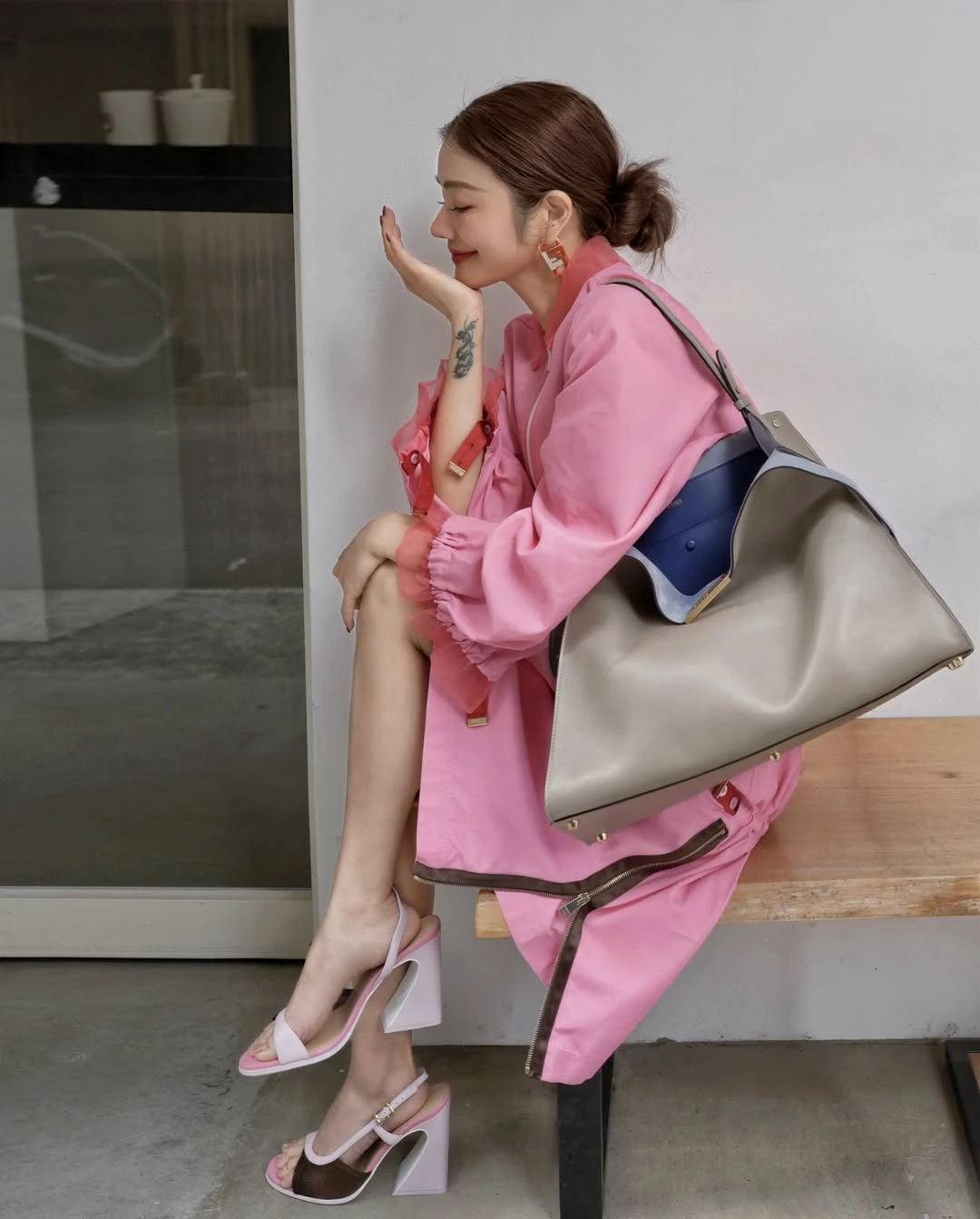 想讓造型看起來更年輕，顏色往往是關鍵。許路兒以 Fendi 粉色拉鍊外套搭配同色系半身裙，利用整體一致的色調營造輕盈感，讓視覺更顯清爽俐落。粉色雖然帶有甜度，但她選擇偏俐落的運動風剪裁，讓造型在柔和與率性之間取得平衡。下身以簡潔拼接設計的高跟涼鞋延伸腿部線條，使整體比例更顯修長。包款則選擇2026春夏大秀全新亮相的 Fendi Way Bag，這款新作以優雅俐落的梯形輪廓搭配雙色皮革設計，外層為低調的鴿灰色，內裡則帶有電光藍的亮點，在極簡之中保留一點驚喜。包身容量實用，線條又十分俐落，既能搭配日常造型，也能延伸到工作場合。對於希望在成熟氣質中保留活力感的女性而言，這種亮色服裝搭配極簡包款的組合，往往能讓整體看起來更精神，也更具現代感。