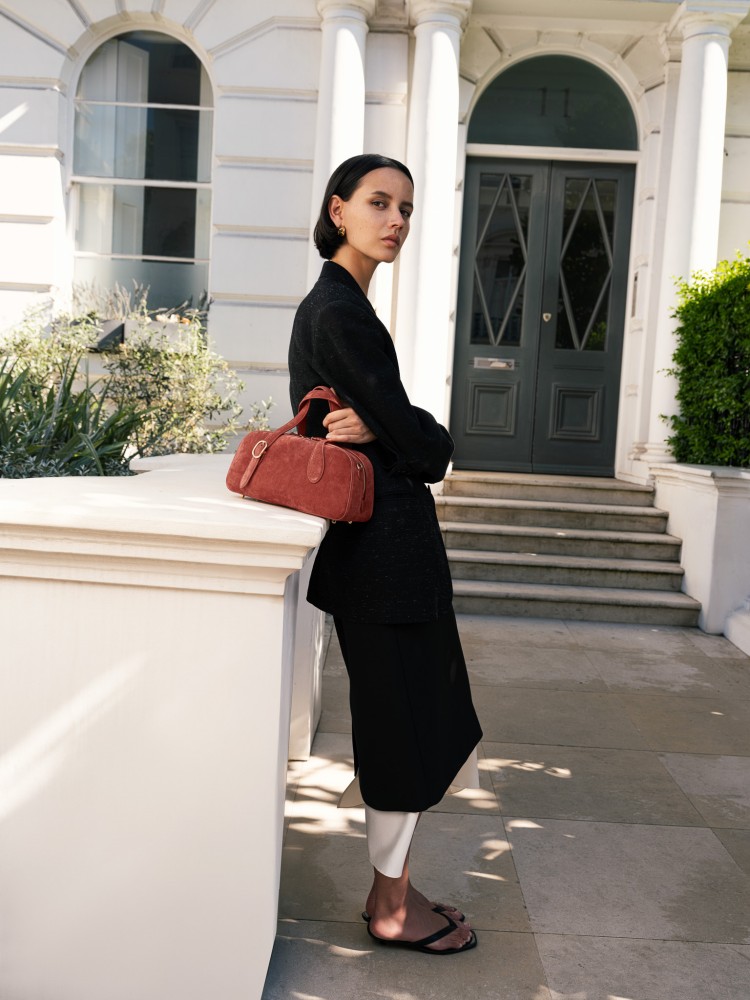 經典波士頓包輪廓為靈感，選用義大利麂皮與光滑小牛皮拼接製成，柔軟細膩的質地在秋冬光影中更顯層次。