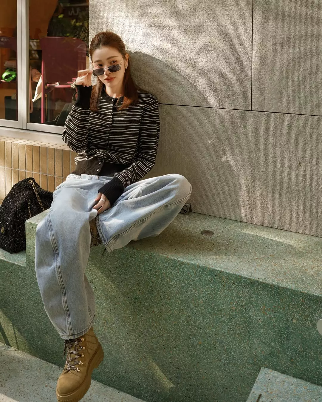 丹寧向來是最容易穿出年輕感的單品，而許路兒很懂得利用「比例」來放大這個效果。她以上海設計師品牌 Slo 的黑色細條紋短版針織上衣搭配高腰寬版牛仔褲，透過短上衣強調腰線，同時讓下半身比例看起來更修長。寬版褲型則帶來一點隨性與鬆弛感，不會過於貼身，也讓整體輪廓顯得更輕鬆。腳下搭配厚底短靴，進一步拉長腿部比例，也為造型增加份量感。這套造型的另一個亮點，是她肩上的 Chanel 25 Tweed Bag，黑色斜紋軟呢材質讓整體更有質感，也呼應上身的黑色調。對於想穿出減齡感的女性來說，這套穿搭非常值得參考，既時髦大方，同時保有青春活力。