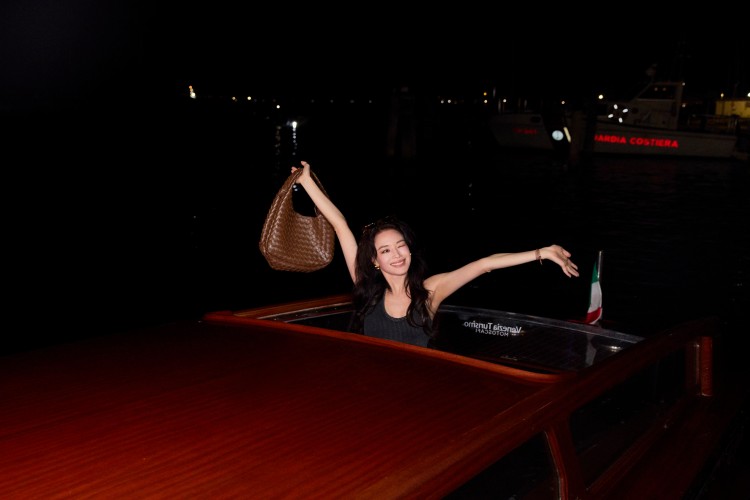 淇更率先以私服示範亮相，以針織背心搭配寬褲，手提焦糖棕Campana與編織登機箱現身威尼斯機場，隨性之中流露從容自信，完美演繹BV女孩的都會魅力。