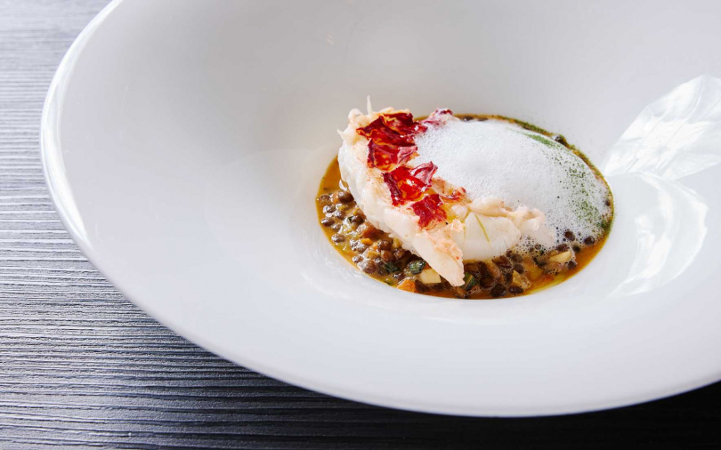 法國藍龍蝦烤至微焦、肉質鮮嫩，搭配蝦高湯與煙燻培根、白色香茅醬，構築多層次香氣。（圖／三二行館提供）