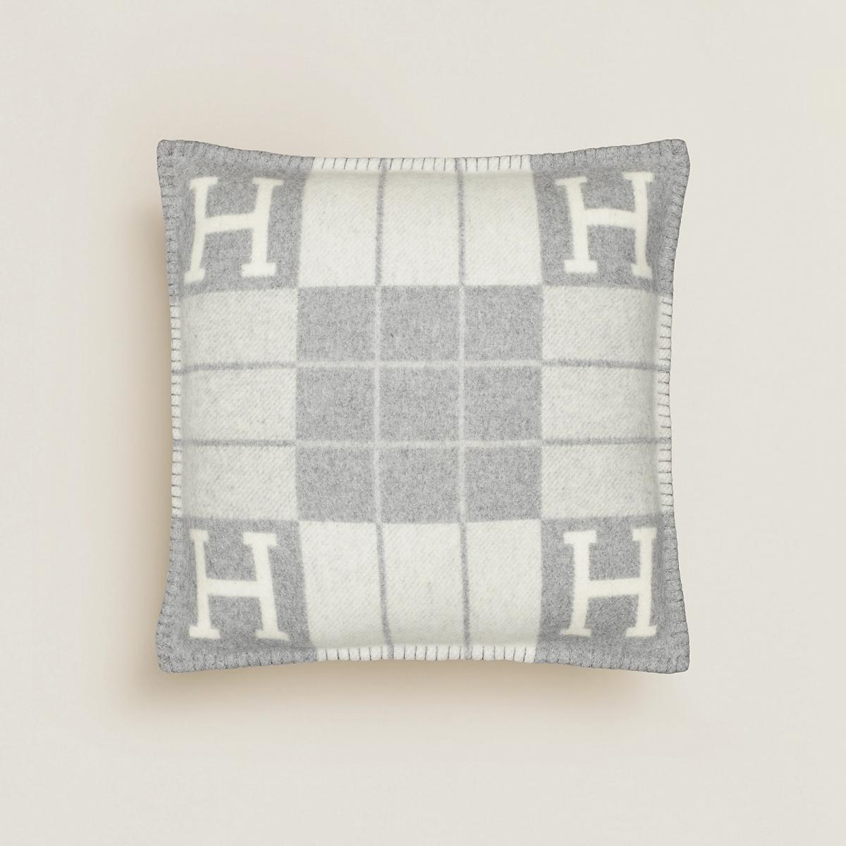 Hermès 經典的 Avalon 系列自1988年問世以來，便成為家飾領域的象徵語言。Avalon III 抱枕將棋盤格紋圖案以緹花織機編織，呈現正反兩面如負片般的趣味反差。