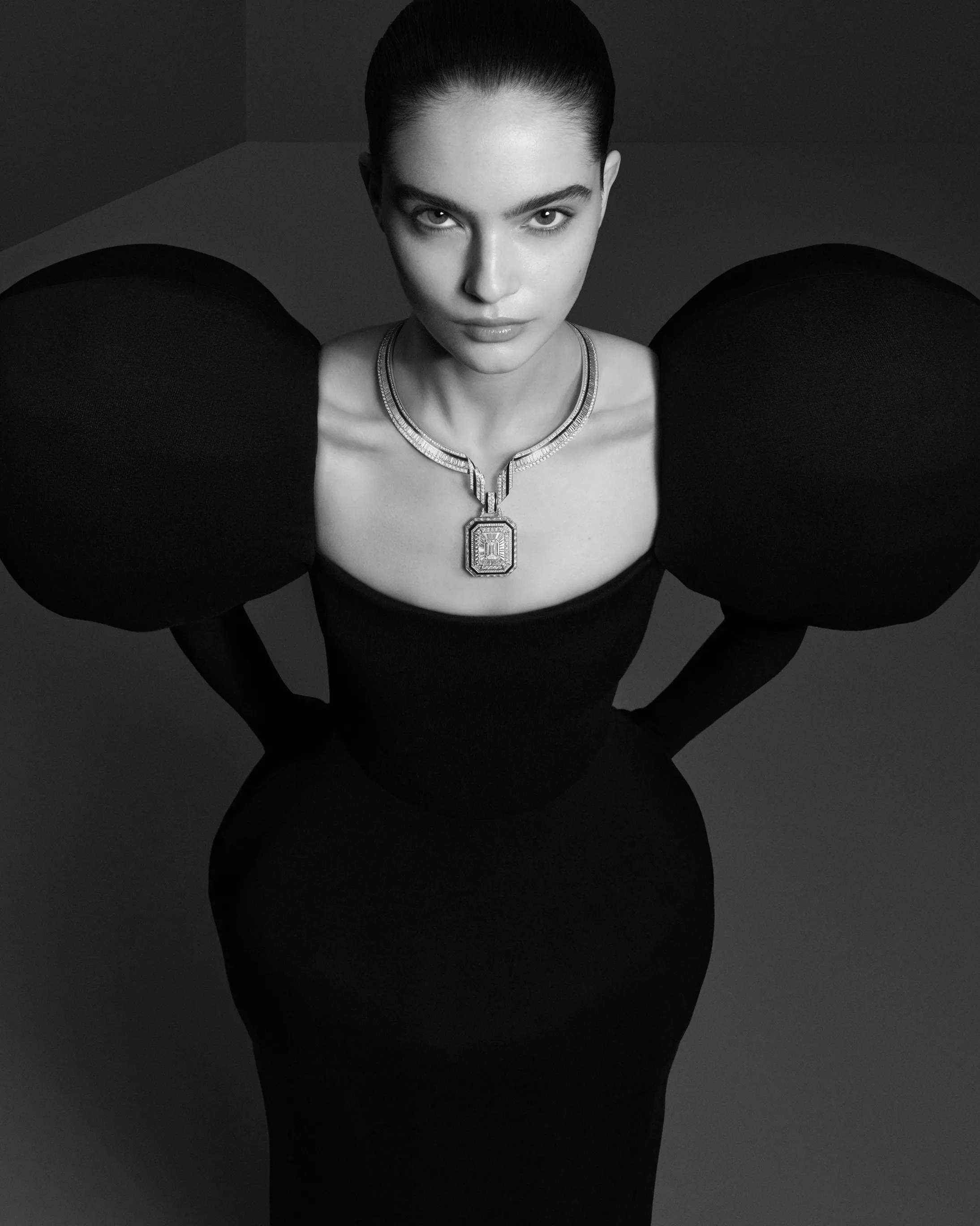 十九世紀末，巴黎和平街（rue de la Paix）匯聚了眾多珠寶與時裝品牌，這條繁忙街道一路延伸，通往當時仍顯靜謐的住宅廣場──Place Vendôme 芳登廣場。這裡是巴黎時髦仕女每日往返杜樂麗花園（Jardin des Tuileries）的必經之路。也因此，當多數商人仍選擇在人潮最密集的街區設點時，寶詩龍先生卻在這條動線與光線交會之處，看見了不同於眾人的可能。1893年，他率先進駐芳登廣場26號。此處一整日灑落的自然光，讓櫥窗中的珍貴寶石得以在無需修飾的狀態下，展現最真實的光彩。這個極具前瞻性的選擇，後來成為高級珠寶產業的關鍵轉折，眾多品牌相繼進駐，也讓芳登廣場逐步成為頂級奢侈的象徵。今年的首件作品〈The Address〉，正是對這個歷史性決定的當代回望。項鍊輪廓取自芳登廣場標誌性的八角形結構，白金與鑽石的單色純粹，對比深邃黑色漆面，彷彿將建築的理性秩序，轉化為一件可隨身體起伏的珠寶作品。它看似冷靜，卻擁有高度柔軟的佩戴結構，而這正是世家一貫的美學理念：在理性與感性之間，取得恰到好處的平衡。