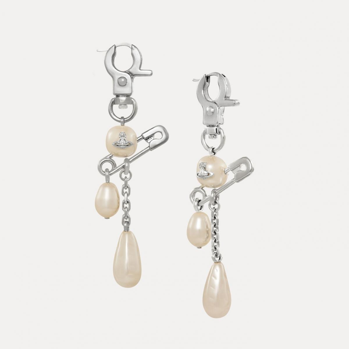 Vivienne Westwood 的 Claude 耳環像一首龐克流行曲。安全別針、珍珠與水滴型吊墜交織，展現出品牌一貫的反叛浪漫。「珍珠的柔」與「金屬的硬」在這裡並存，象徵女性既能溫柔也能堅定。輕盈的設計讓佩戴毫無負擔，搭配襯衫或皮外套都能散發不經意的酷感。