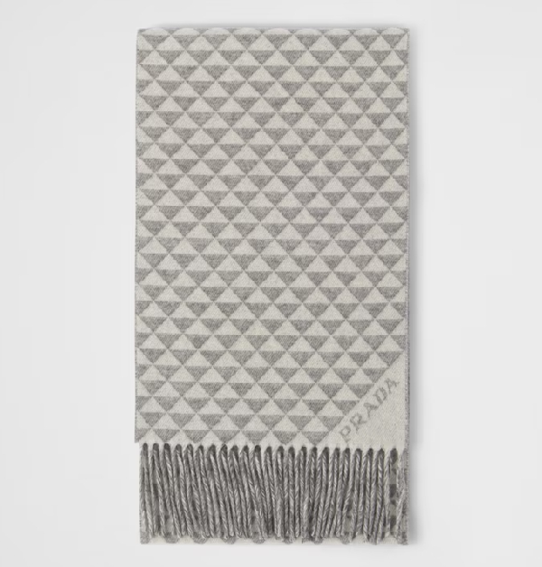 提到Prada代表性的標誌設計，首先就會聯想到經典的「Symbole Logo」三角形盾牌，品牌以此為靈感，將三角圖騰重複編排，搭配對角的緹花標誌，為圍巾增添獨特韻味。