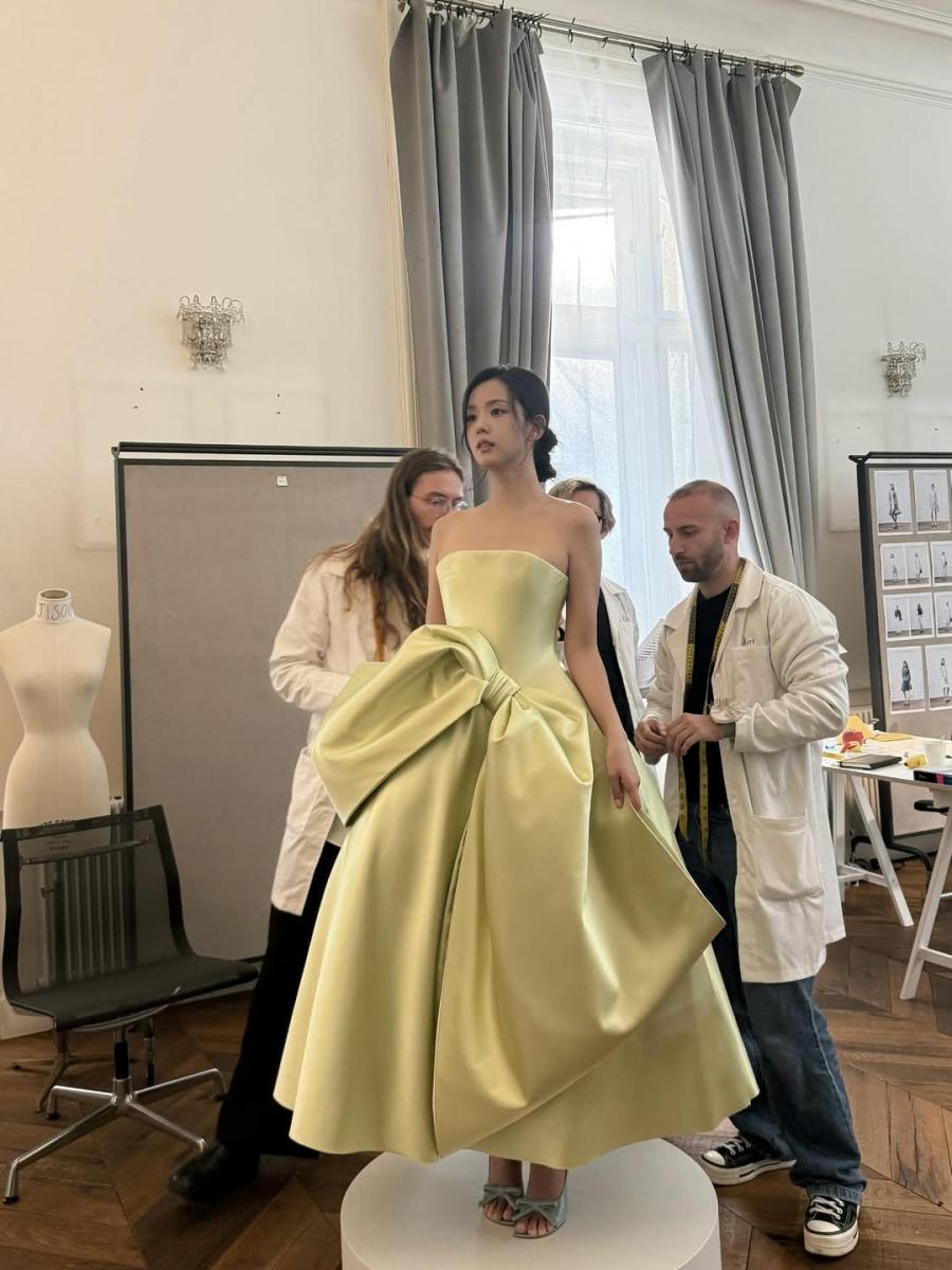 故事回溯至 1950 年代，迪奧先生曾在一套訂製服中，於腰間裝飾一只大蝴蝶結，藉此創造出收腰的輪廓。而在 Jonathan Anderson 的首場女裝大秀之前，他亦復刻了這項禮服設計，為品牌大使 Jisoo 設計了一件蝴蝶結禮服，以此致敬品牌歷史。