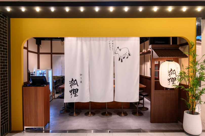 在僅有12個板前座位的日式居酒屋店裝風格下，入口門框以圓弧造型搭配棕黃色系來呈現如狐狸的身形，顯得格外俏皮。
