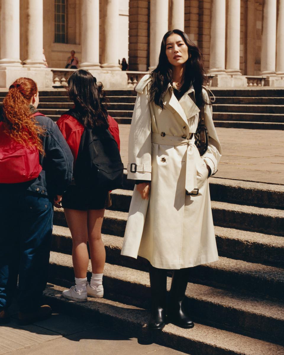 超模劉雯挑選了一件下擺散狀的風衣外套，並搭配上一雙軍靴，讓風衣以類似過膝洋裝的形式呈現，整體變得個性、又率性。