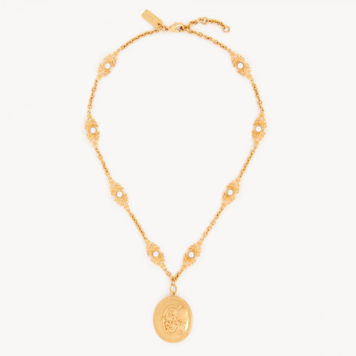 Chloé 的 Château Treasures 項鍊，帶著一種宛如從古董珠寶盒中取出的浪漫氣息。復古金色黃銅鏈條上鑲嵌了「C」字花朵徽章，並點綴上小巧的樹脂珍珠，層層堆疊出女性柔美的姿態。