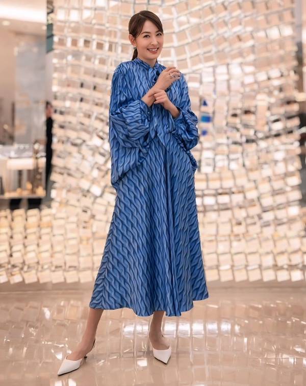 賈永婕的這套穿搭，又再次示範了何謂「穿得減齡而不失層次」。誰說長洋裝穿起來會顯得老氣沉重？就像她身著這襲寶藍色印花洋裝，巧妙利用幾何波紋的縱向視覺流動感，打破了長洋裝容易帶來的沉重感，反而賦予整體造型一種如水般的靈動氣息。
