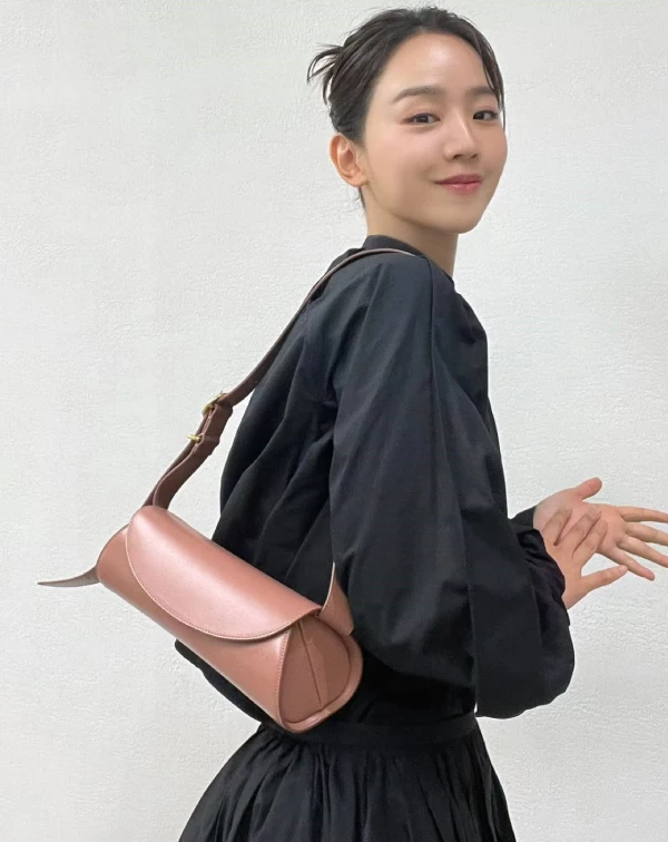 申惠善以簡約的黑色連身裙完美襯托出Jil Sander經典的「Cannolo」圓滾造形肩包。這款包以其圓滾滾的柱形輪廓而聞名，靈感取自於義大利西西里島的傳統甜點「奶油捲」，展現了品牌一貫的極簡主義與幾何美學。