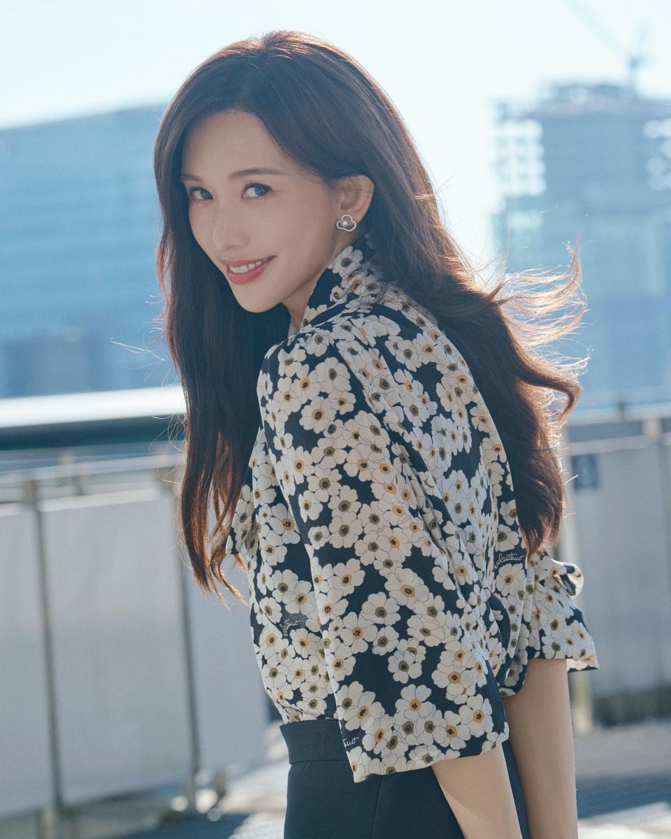 林志玲以黑白小花襯衫配俐落黑裙亮相，陽光勾勒出她一貫的清新優雅。耳畔佩戴 TASAKI chants 阿古屋珍珠與18K白金鑲鑽耳環；指間則是 balance decade 南洋珍珠戒指，五顆珍珠水平排佈，象徵平衡與力量。